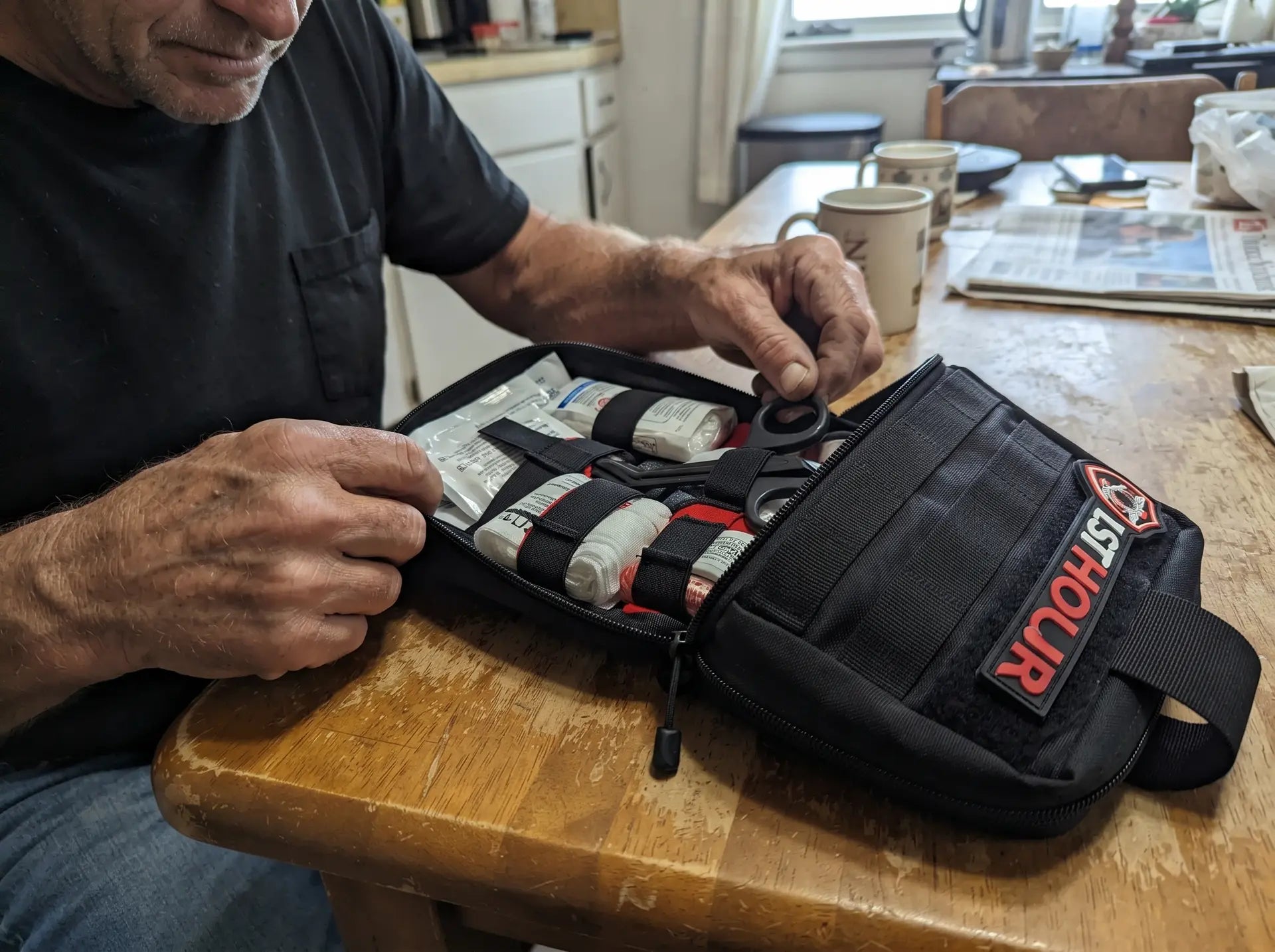 Hands opening the 1stHour kit showing the organized MOLLE interior